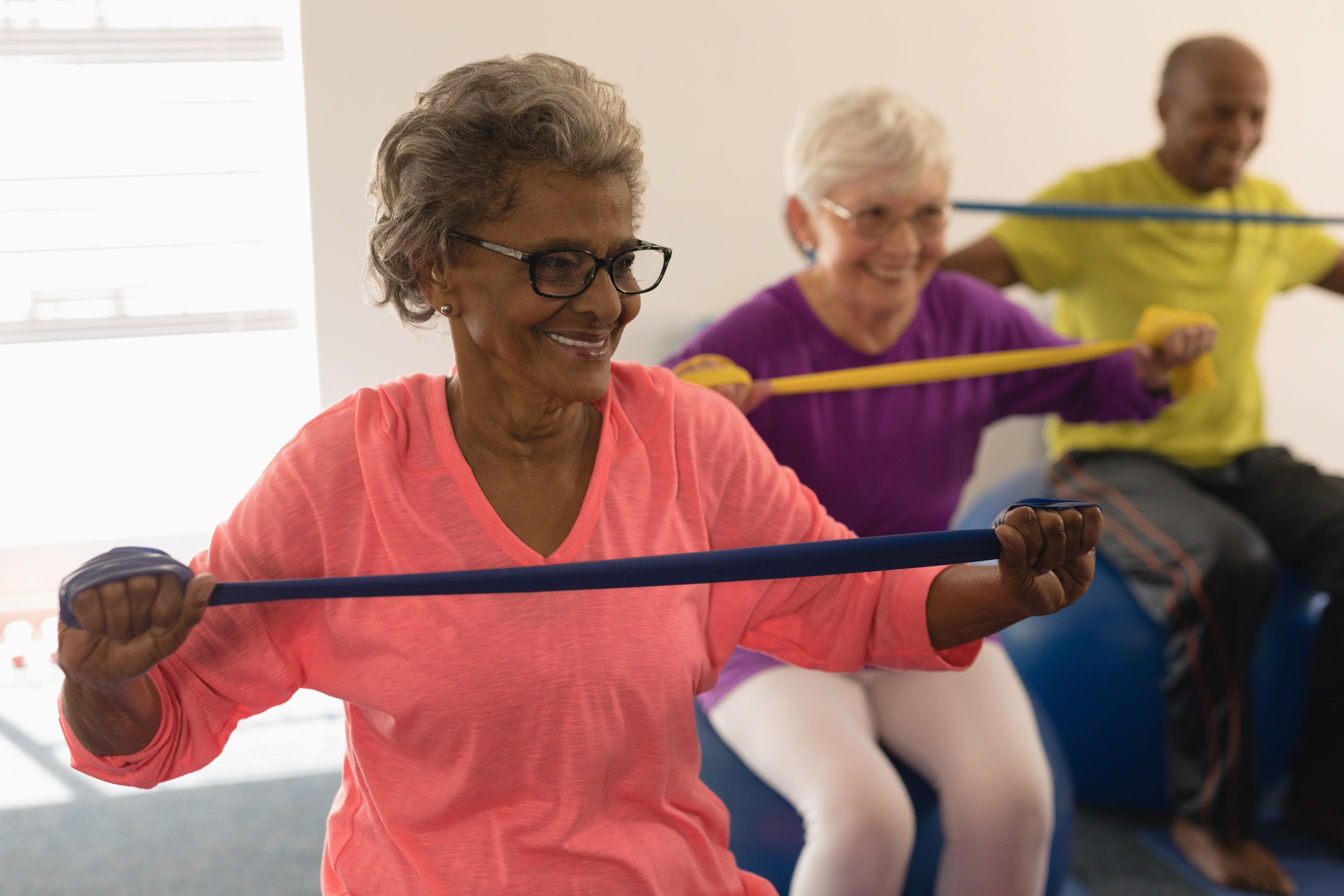 Seniors exercise with resistance bands in fitness studio.